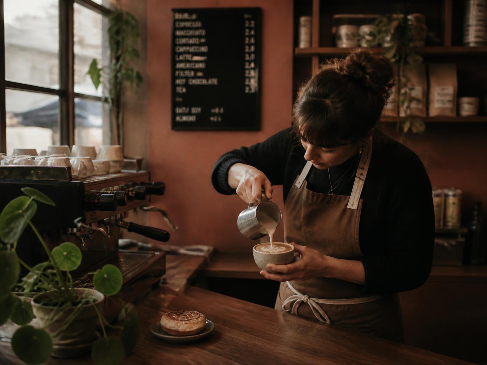 Barista at Cafe Inspire pouring latte art into a ceramic cup